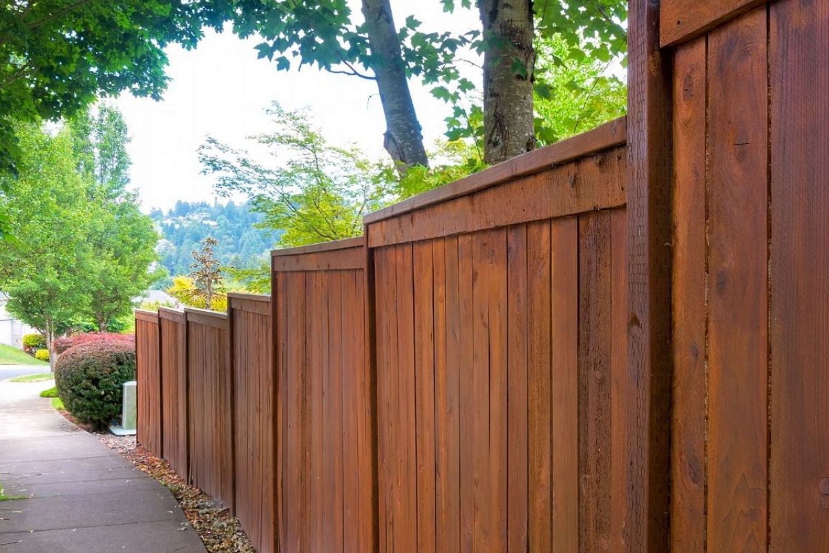stained wood fence along a sidewalk